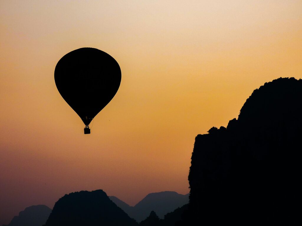 A hot air balloon floats in silhouette against a vibrant sunrise in Vang Vieng, Laos.
